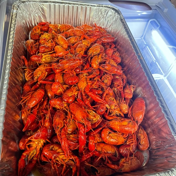 A large foil pan filled with many bright red, cooked crawfish, ready to be served.