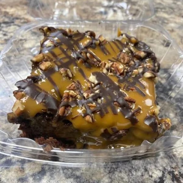 A Delta Fish Market dessert, a brownie topped with caramel, chocolate drizzle, and chopped nuts.