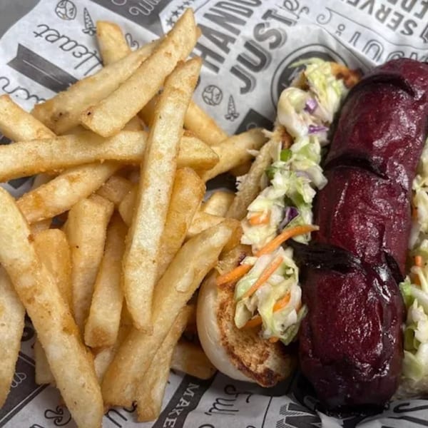 Delta Fish Market's hot dog with dark red sauce and coleslaw, served with golden fries.